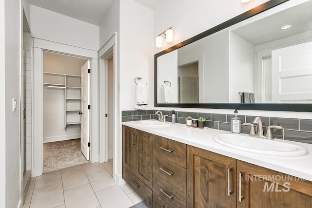 bathroom featuring tile patterned flooring, vanity, backsplash, and an enclosed shower