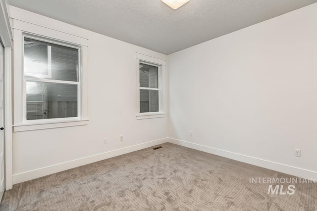 carpeted spare room featuring a textured ceiling