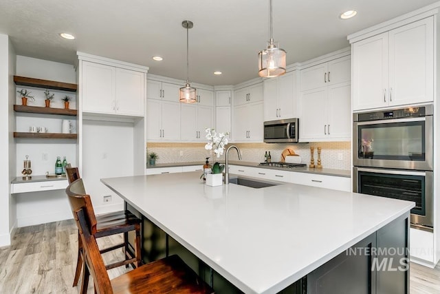 kitchen with stainless steel appliances, sink, a center island with sink, and white cabinets