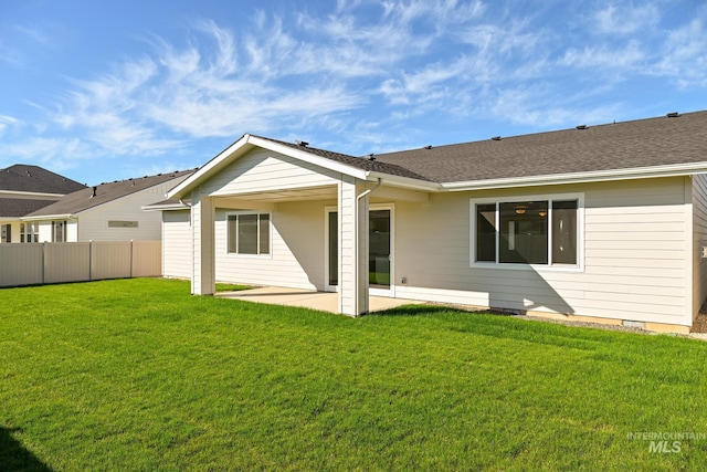 rear view of property with a patio area, a lawn, a shingled roof, and fence