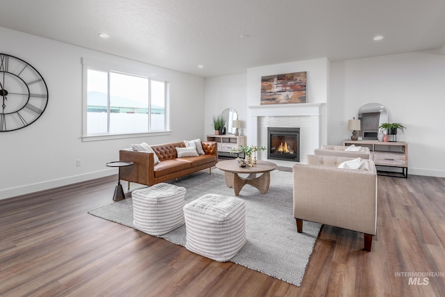 living room featuring a glass covered fireplace, baseboards, and wood finished floors