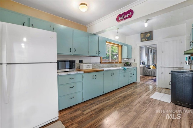 353 7th Ave E, Twin Falls, ID 83301 - kitchen with freestanding refrigerator, stainless steel microwave, blue cabinetry, dark wood-style flooring, and light countertops