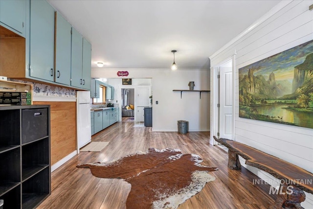353 7th Ave E, Twin Falls, ID 83301 - kitchen with blue cabinetry, freestanding refrigerator, wood finished floors, crown molding, and a sink