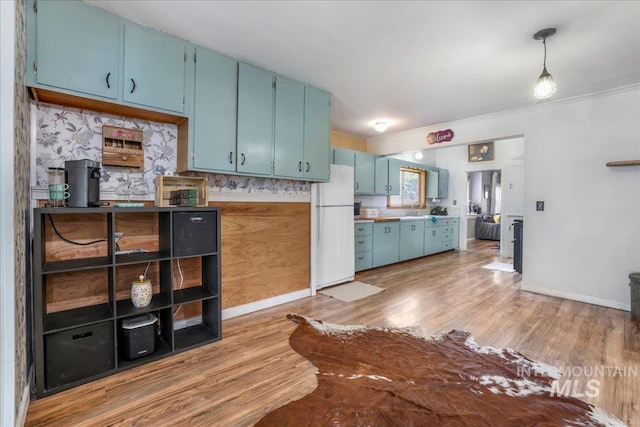 353 7th Ave E, Twin Falls, ID 83301 - kitchen with freestanding refrigerator, blue cabinets, light wood finished floors, a sink, and crown molding