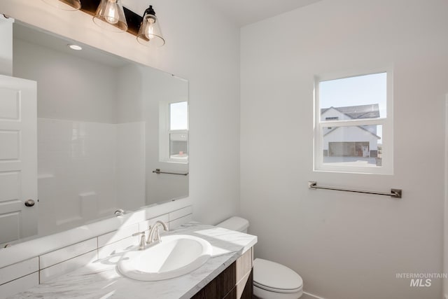 bathroom with a healthy amount of sunlight, vanity, and toilet