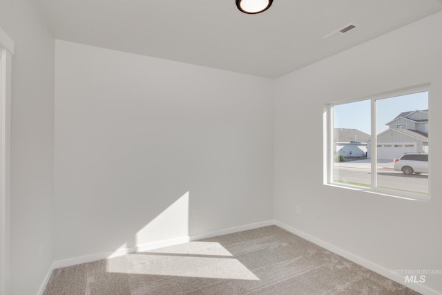 spare room featuring visible vents, baseboards, and light colored carpet