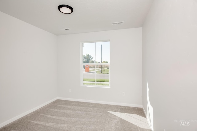 spare room with carpet floors, visible vents, and baseboards