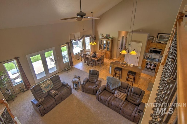 living room with light hardwood / wood-style floors, high vaulted ceiling, and ceiling fan