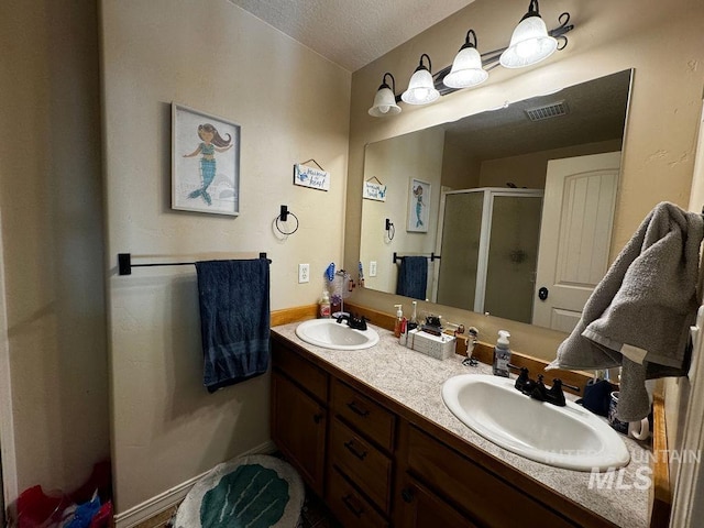 bathroom with vanity, a textured ceiling, and an enclosed shower