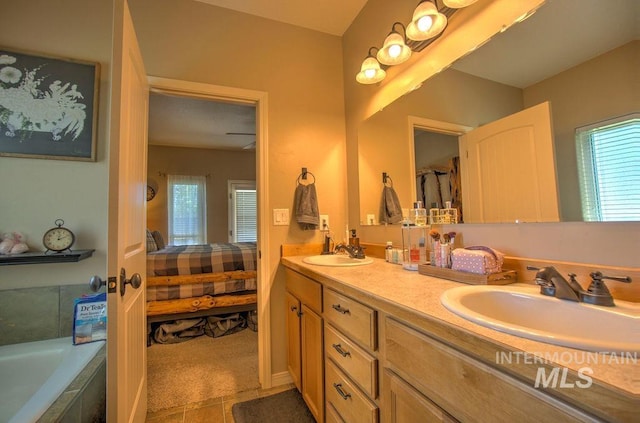 bathroom featuring tiled tub, vanity, and tile patterned flooring