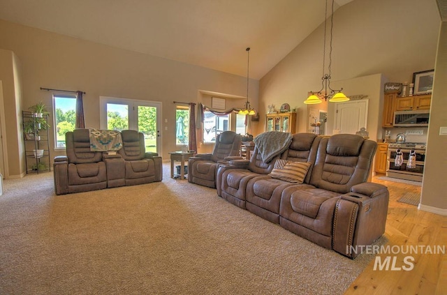 carpeted living room with a chandelier and high vaulted ceiling