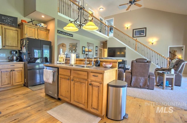 kitchen with light wood-type flooring, high vaulted ceiling, sink, black fridge, and dishwasher