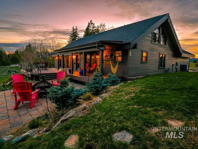 986 Valley Rim Rd, Mccall, ID 83638 - rear view of property featuring a yard, central AC, a wooden deck, roof with shingles, and a patio area