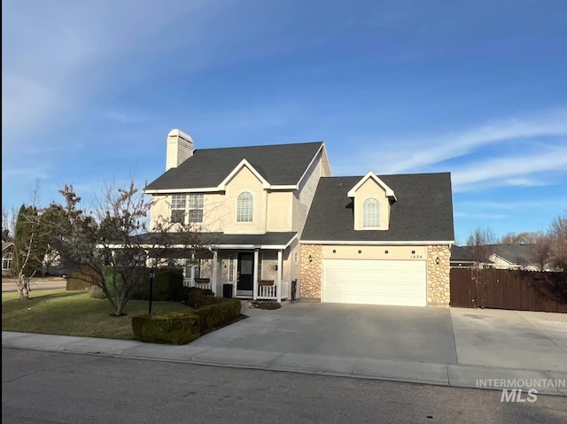 view of front of property with a chimney, covered porch, concrete driveway, fence, and stone siding