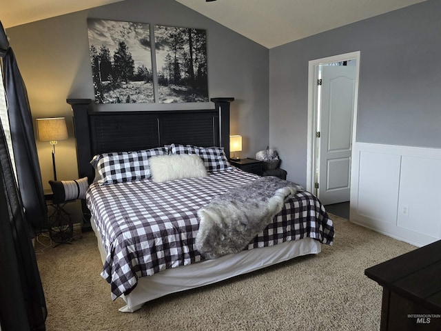 carpeted bedroom featuring lofted ceiling and a wainscoted wall