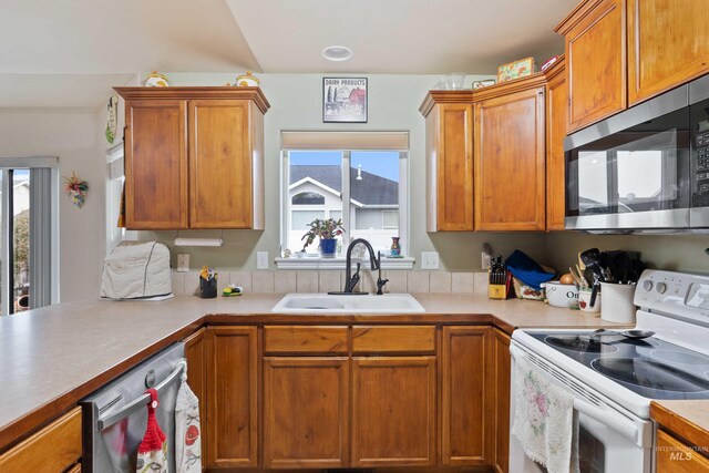 kitchen with appliances with stainless steel finishes, a sink, and light countertops