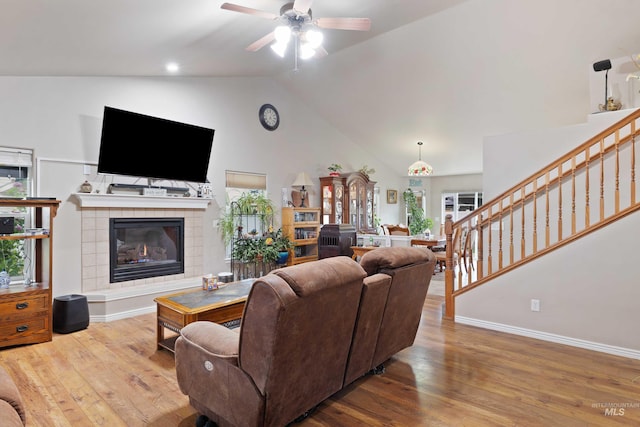 living room with a ceiling fan, wood finished floors, stairway, baseboards, and a tile fireplace