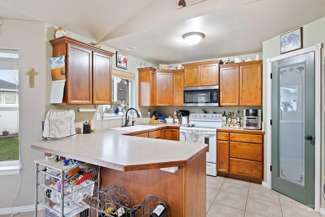 kitchen with stainless steel microwave, white electric range, a sink, a peninsula, and light countertops