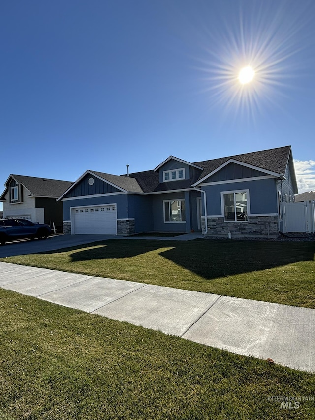 view of front facade with a garage, stone siding, board and batten siding, and a front yard