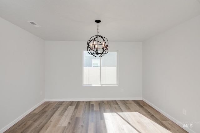 11075 W Windmill Way, Nampa, ID 83651 - spare room featuring a notable chandelier, baseboards, visible vents, and wood finished floors