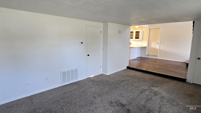 carpeted empty room featuring a textured ceiling