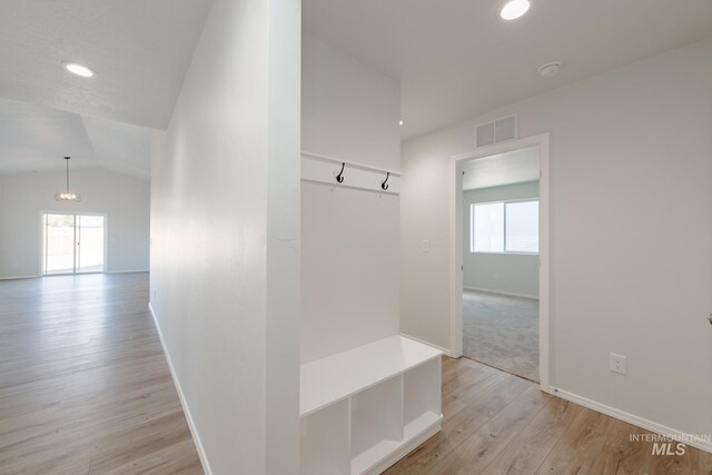 mudroom with light wood-type flooring, visible vents, baseboards, and vaulted ceiling