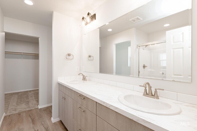 full bath with a shower stall, double vanity, visible vents, and a sink