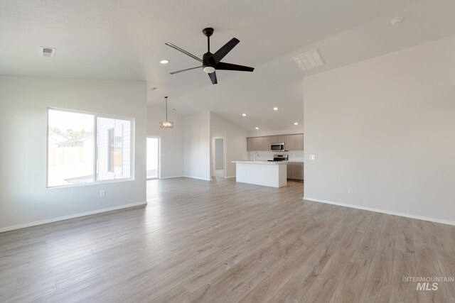 unfurnished living room featuring a ceiling fan, baseboards, visible vents, light wood finished floors, and a sink