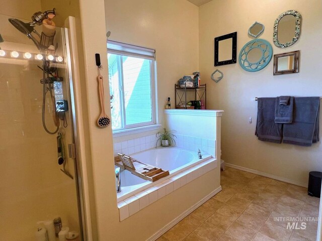 bathroom with a bath, a stall shower, and baseboards