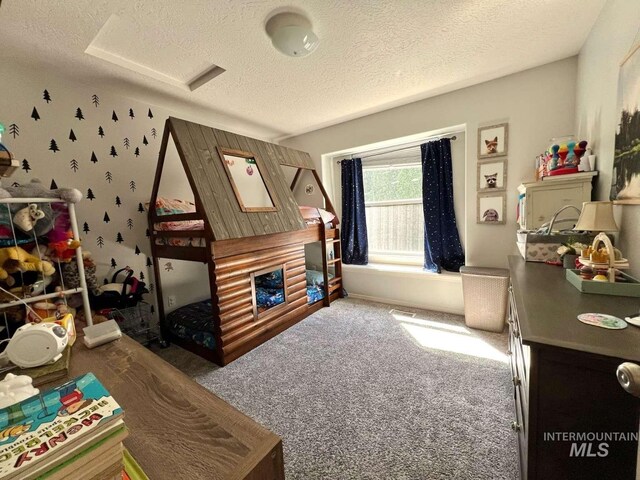 carpeted bedroom with a textured ceiling and attic access