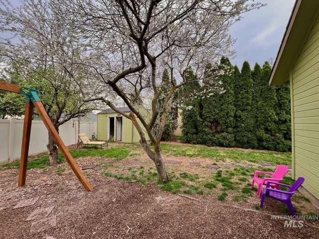 view of yard with a storage shed, an outbuilding, and fence