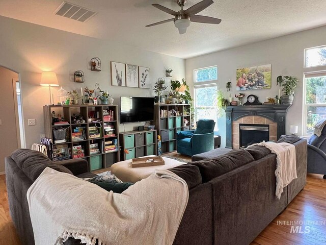living room featuring visible vents, ceiling fan, plenty of natural light, and wood finished floors