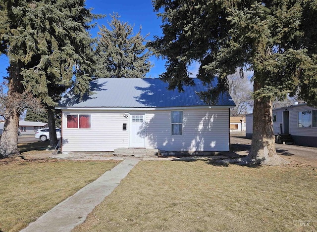 view of front of house featuring metal roof and a front yard