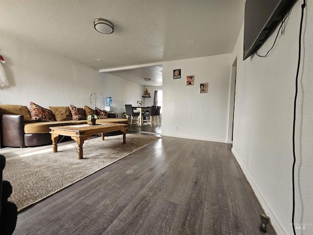 living area with hardwood / wood-style flooring, a textured wall, baseboards, and a textured ceiling