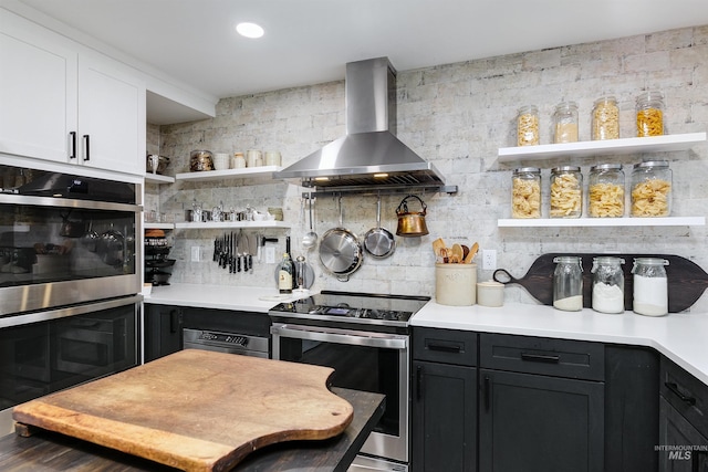 kitchen featuring appliances with stainless steel finishes, white cabinets, wall chimney range hood, and decorative backsplash