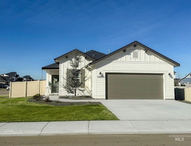 view of front of house featuring concrete driveway, board and batten siding, a front yard, fence, and a garage