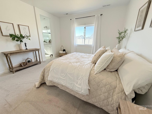 carpeted bedroom featuring connected bathroom, visible vents, and baseboards