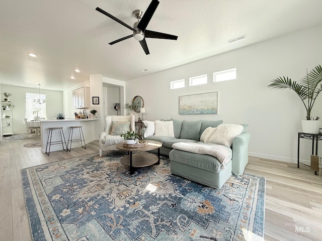 living area with a ceiling fan, visible vents, light wood-style flooring, and baseboards