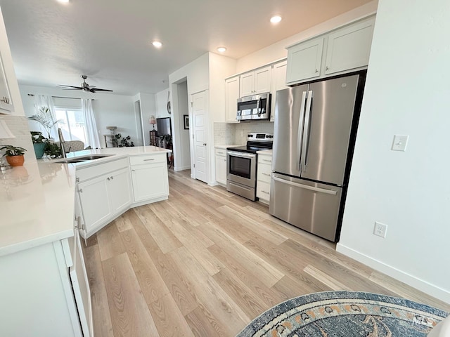 kitchen featuring light wood-style floors, decorative backsplash, stainless steel appliances, and a sink