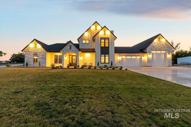 modern farmhouse style home with stone siding, a front lawn, board and batten siding, and an attached garage