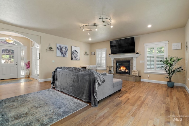 6114 N Cape Arago Pl, Boise, ID 83714 - living area featuring light wood-style flooring, baseboards, a tiled fireplace, arched walkways, and recessed lighting