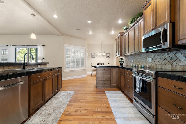 6114 N Cape Arago Pl, Boise, ID 83714 - kitchen with stainless steel appliances, a sink, light wood-type flooring, hanging light fixtures, and backsplash