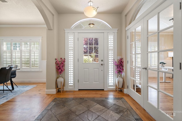 6114 N Cape Arago Pl, Boise, ID 83714 - foyer entrance featuring arched walkways, wood finished floors, a textured ceiling, baseboards, and crown molding