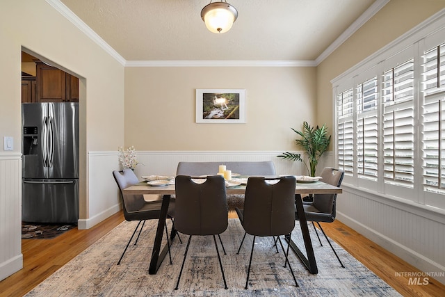 6114 N Cape Arago Pl, Boise, ID 83714 - dining room with light wood-type flooring, a wainscoted wall, and ornamental molding