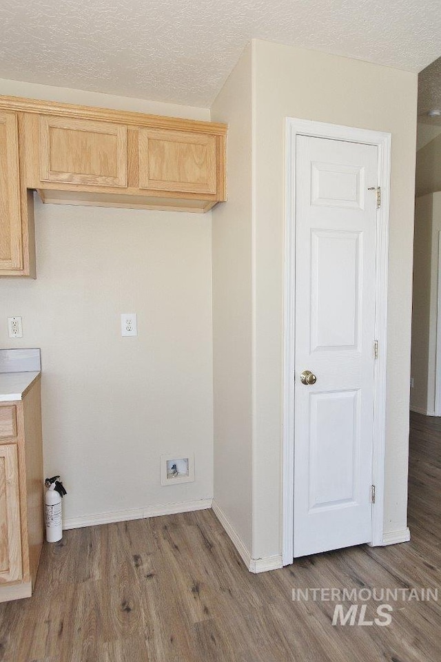 washroom featuring baseboards, a textured ceiling, wood finished floors, and laundry area