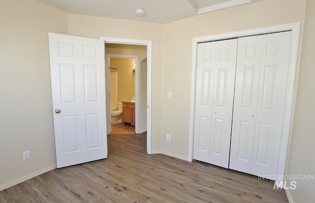 unfurnished bedroom with baseboards, wood finished floors, and a closet