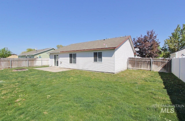 rear view of house with a fenced backyard, a patio area, and a yard