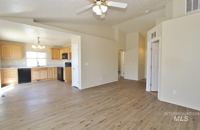 unfurnished living room with a sink, light wood finished floors, arched walkways, a textured ceiling, and visible vents