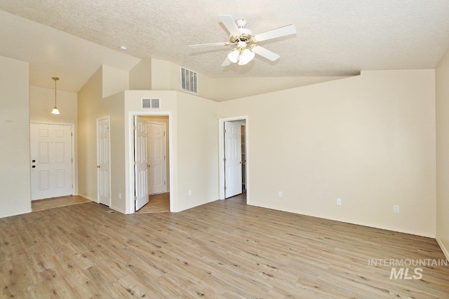 spare room featuring ceiling fan, light wood finished floors, a textured ceiling, and visible vents