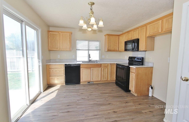 kitchen with an inviting chandelier, a sink, black appliances, and light brown cabinets